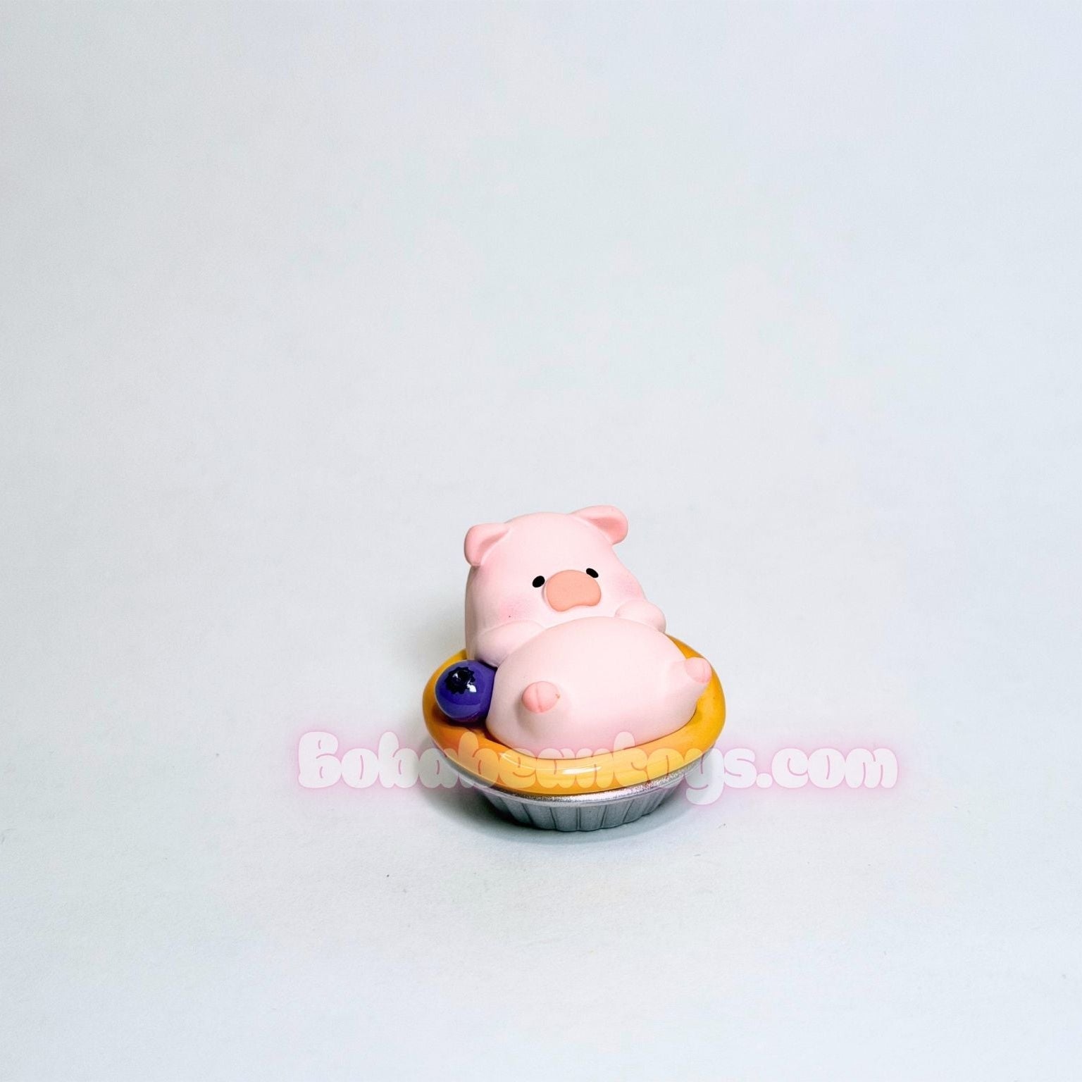 Pink piggy sitting on an egg tart on a white background