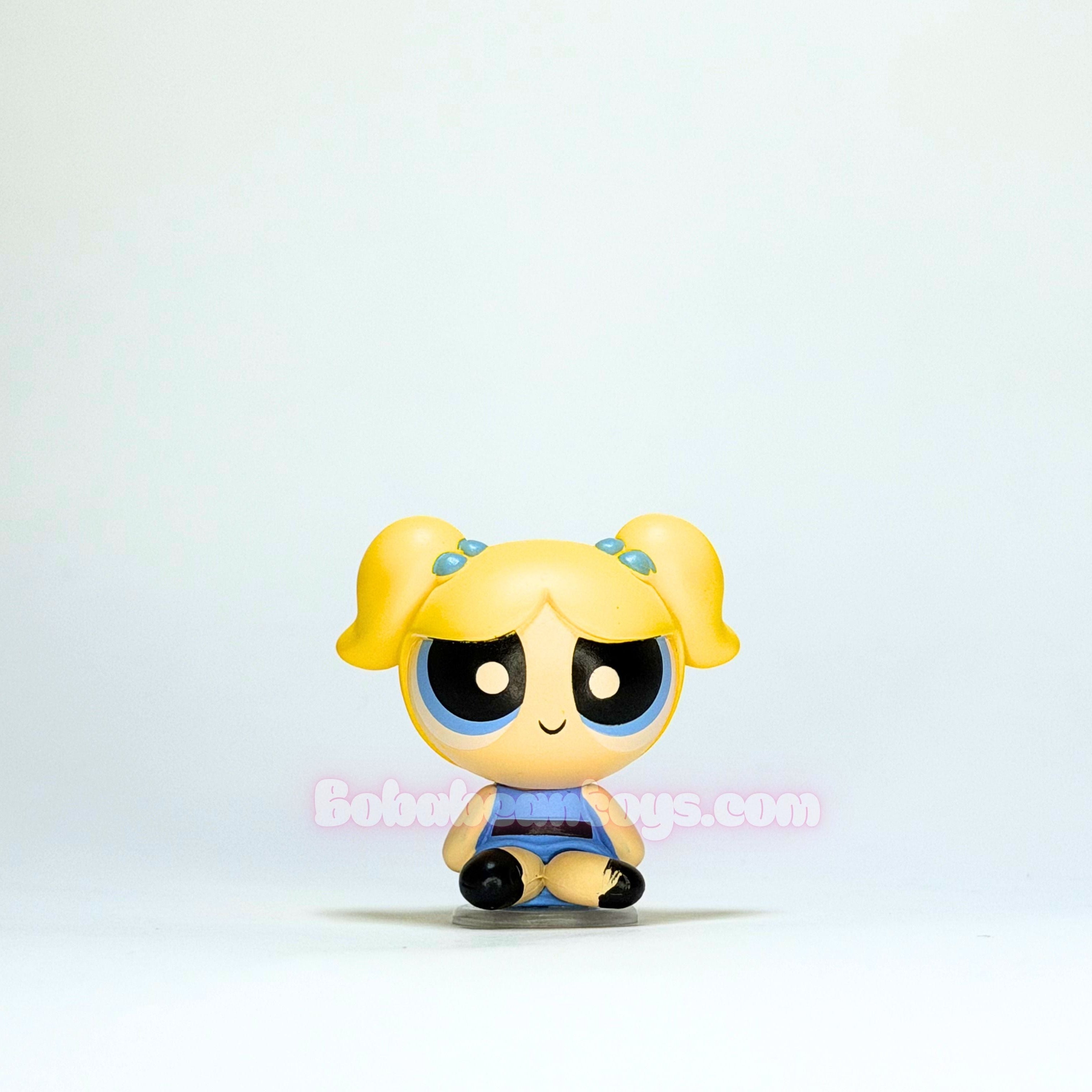Small figurine with yellow hair and black eyes on a light blue background