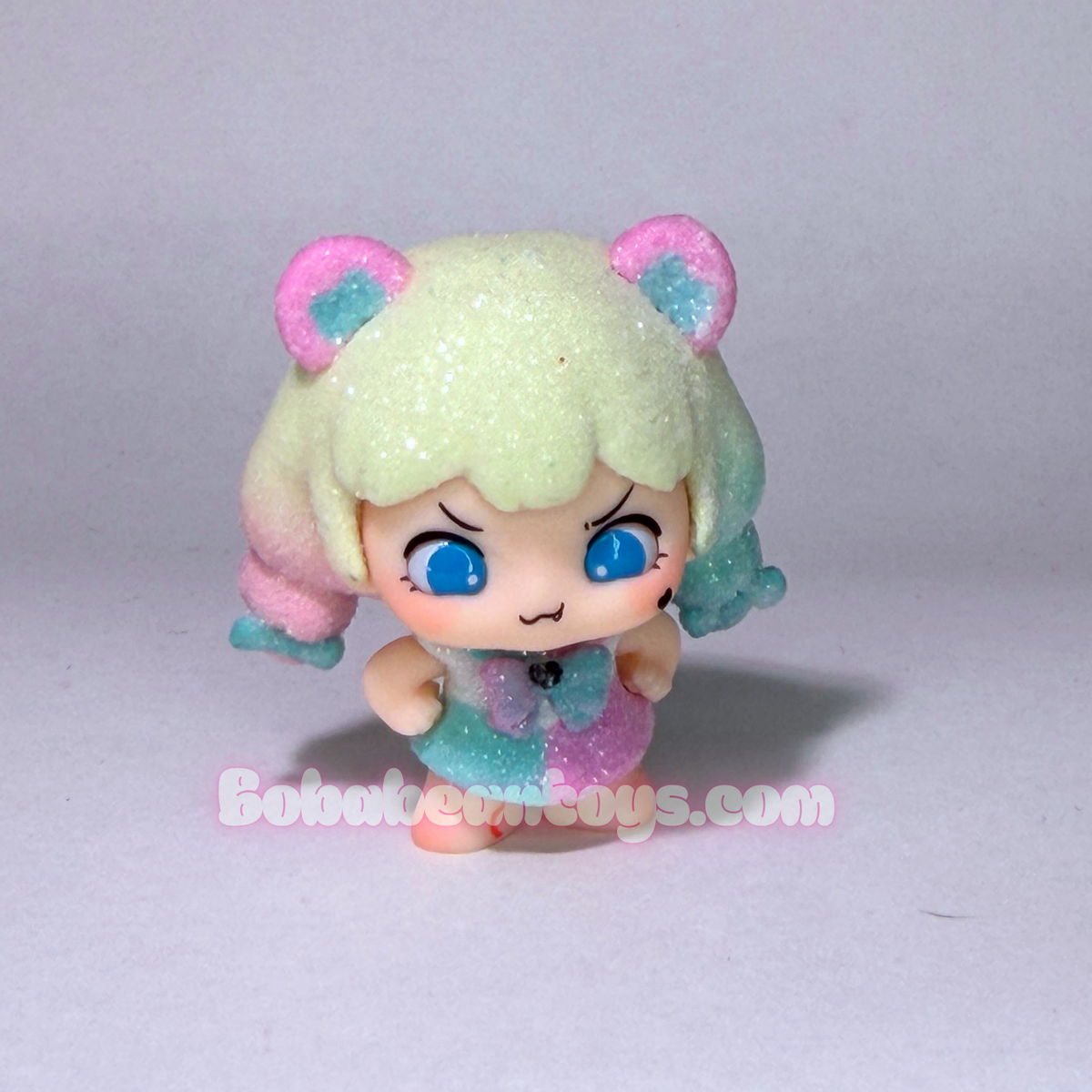 A small anime-style chibi figurine with purple hair, cat ears, and a lavender outfit, photographed against a plain light gray background. A watermark reading Bobabeantoys.com