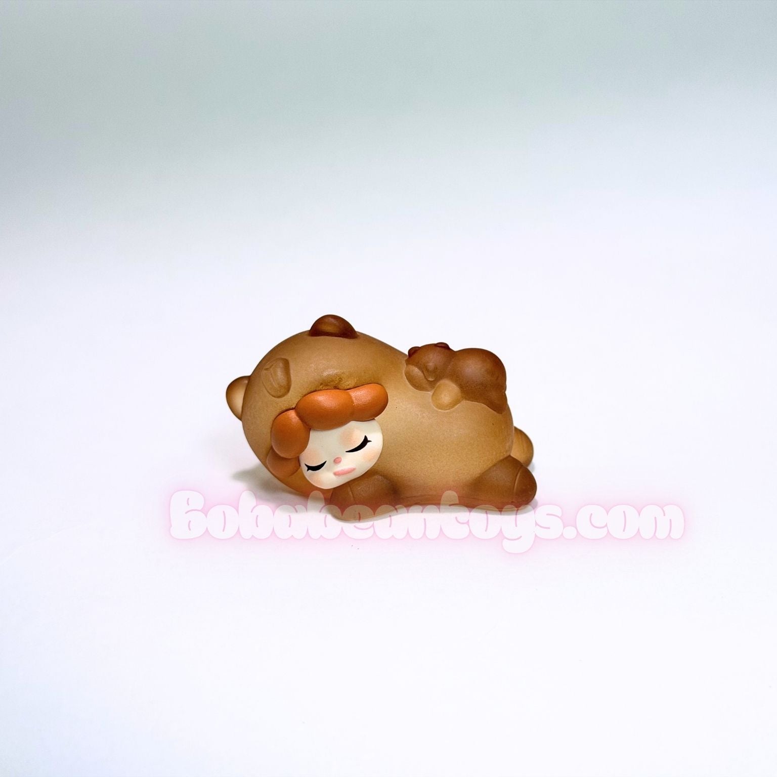 Small brown capybara figurine with a white face on a light gray background