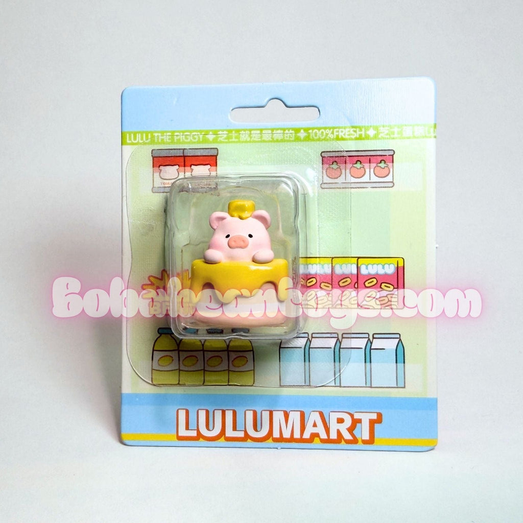 Toy figure of a pig in a yellow hat on a Lulumart packaging background