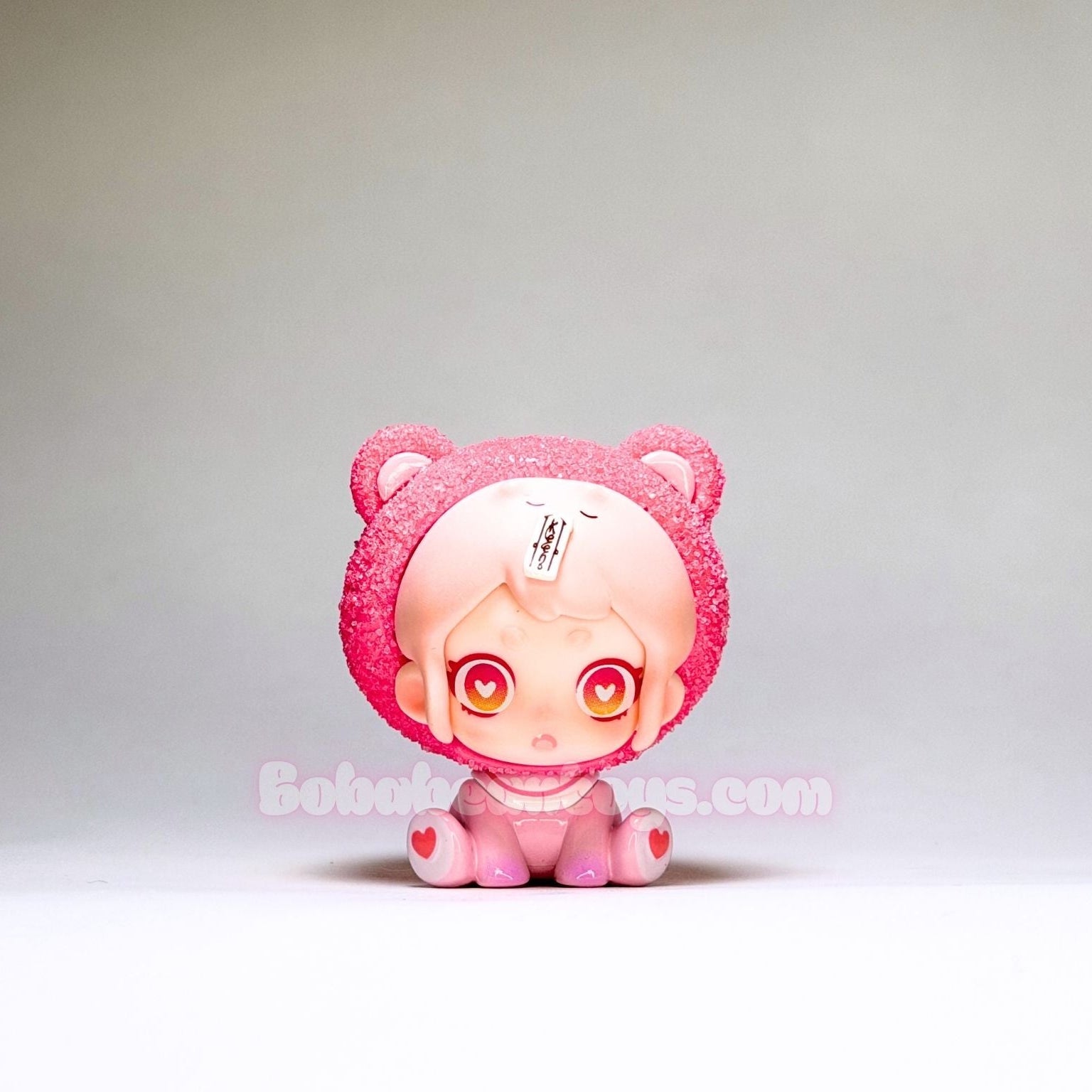 Small pink character figurine with a plain background