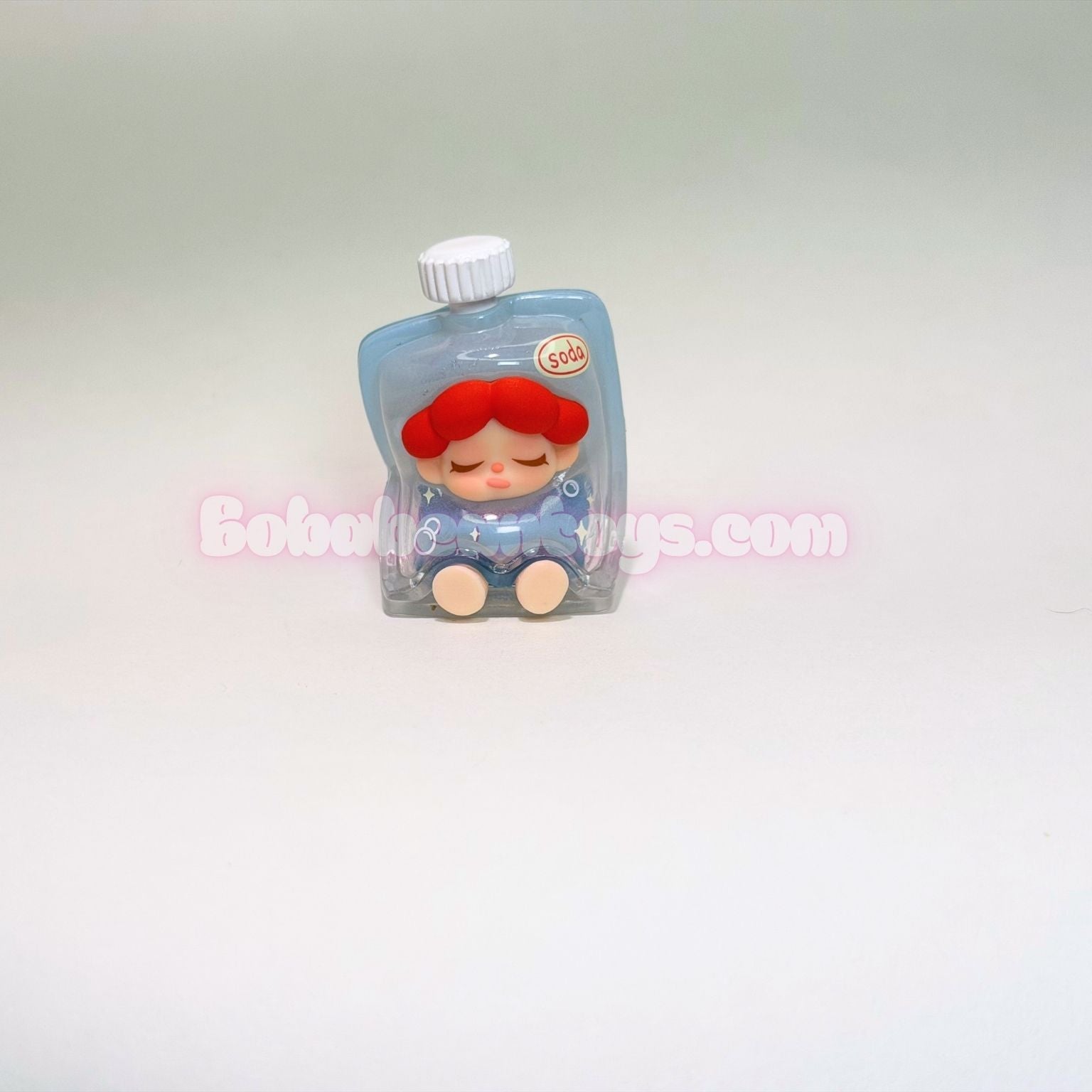 Small figurine in a clear packaging on a light gray background