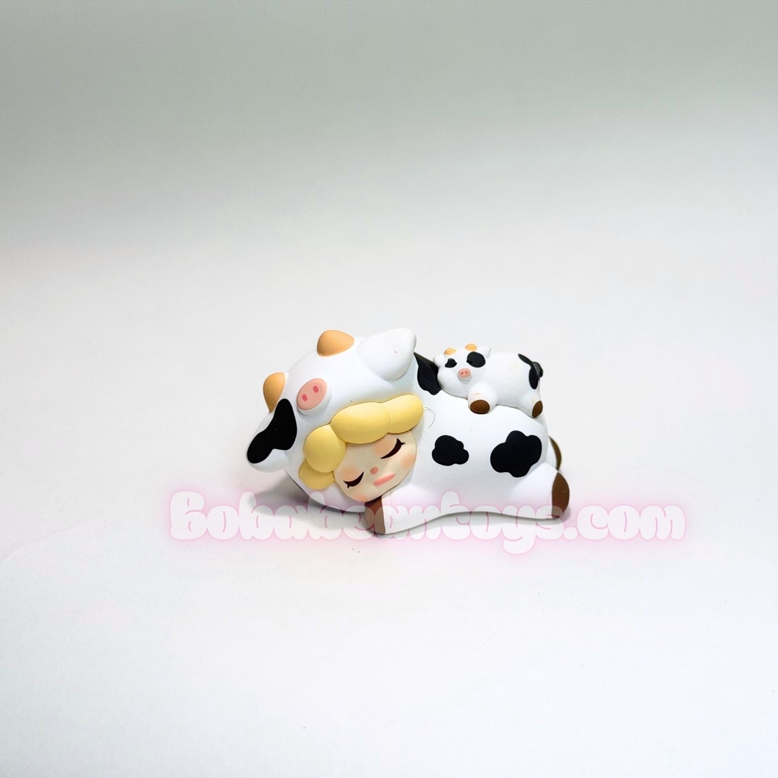Two small figurines resembling a cow and a person with a white background