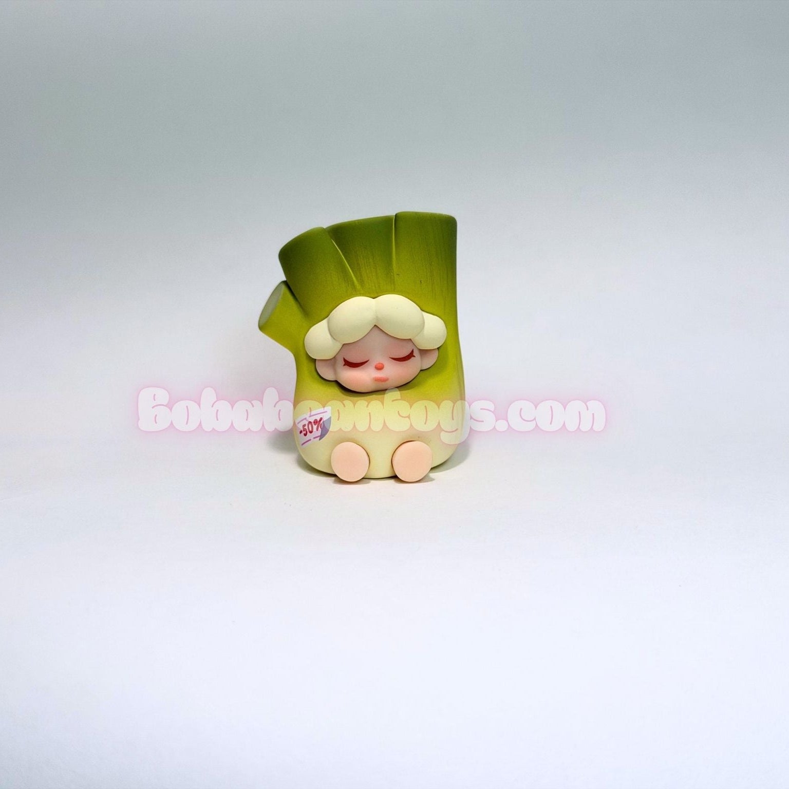 Small figurine of a character dressed as a rotting green onion on a white background