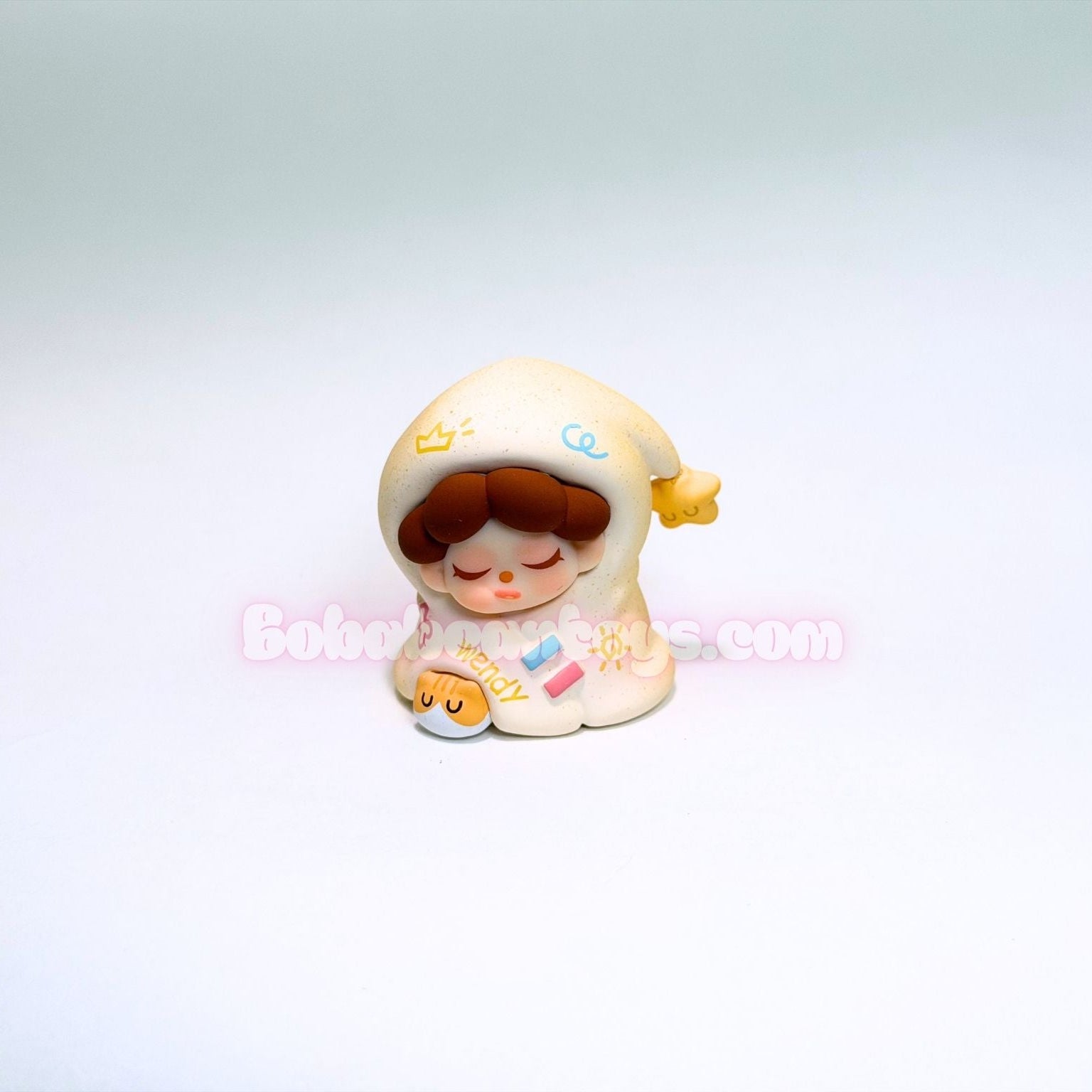 Small figurine of a child in a yellow blanket with a white background