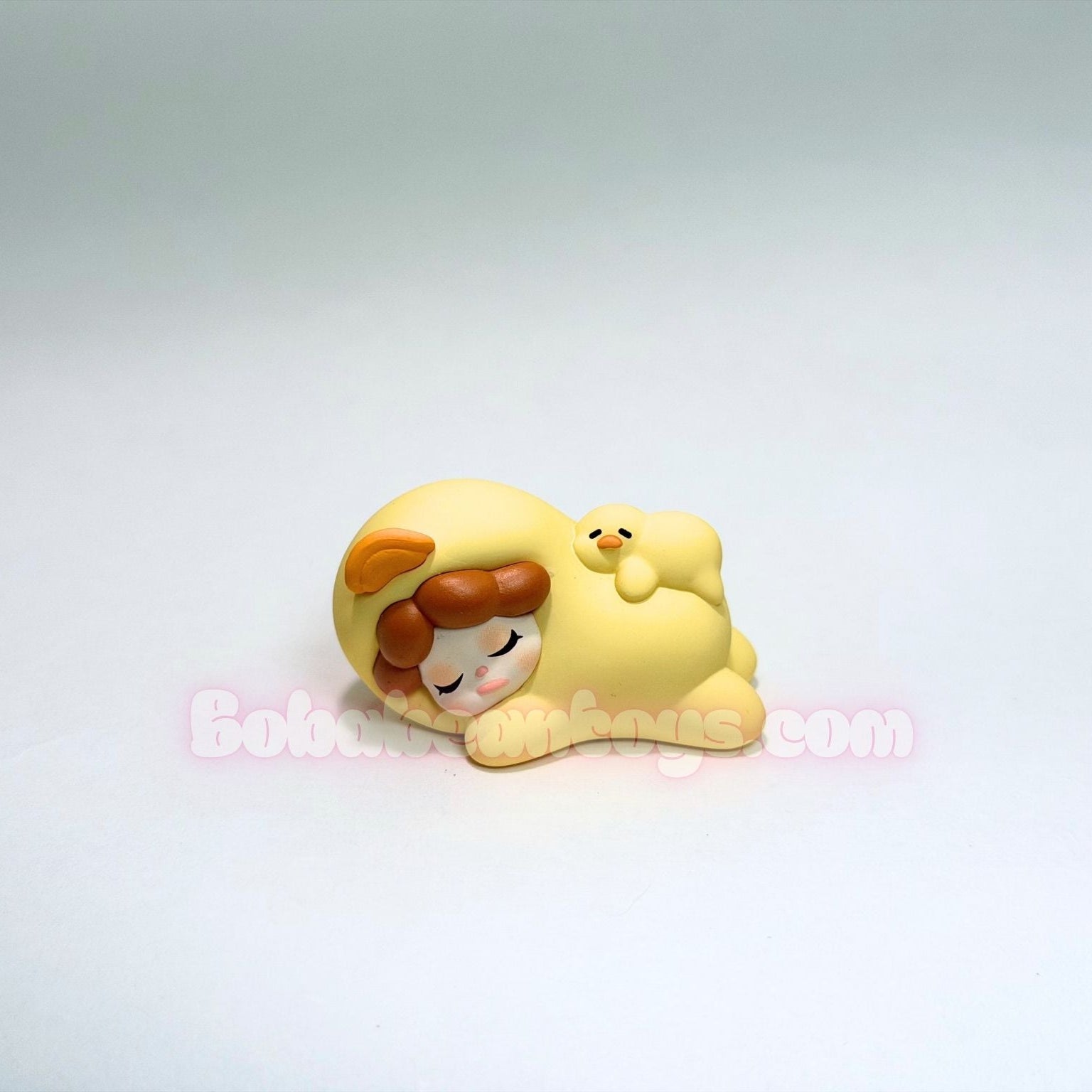 Small figurine of a cartoon character with a yellow duck outfit and brown hair on a white background.