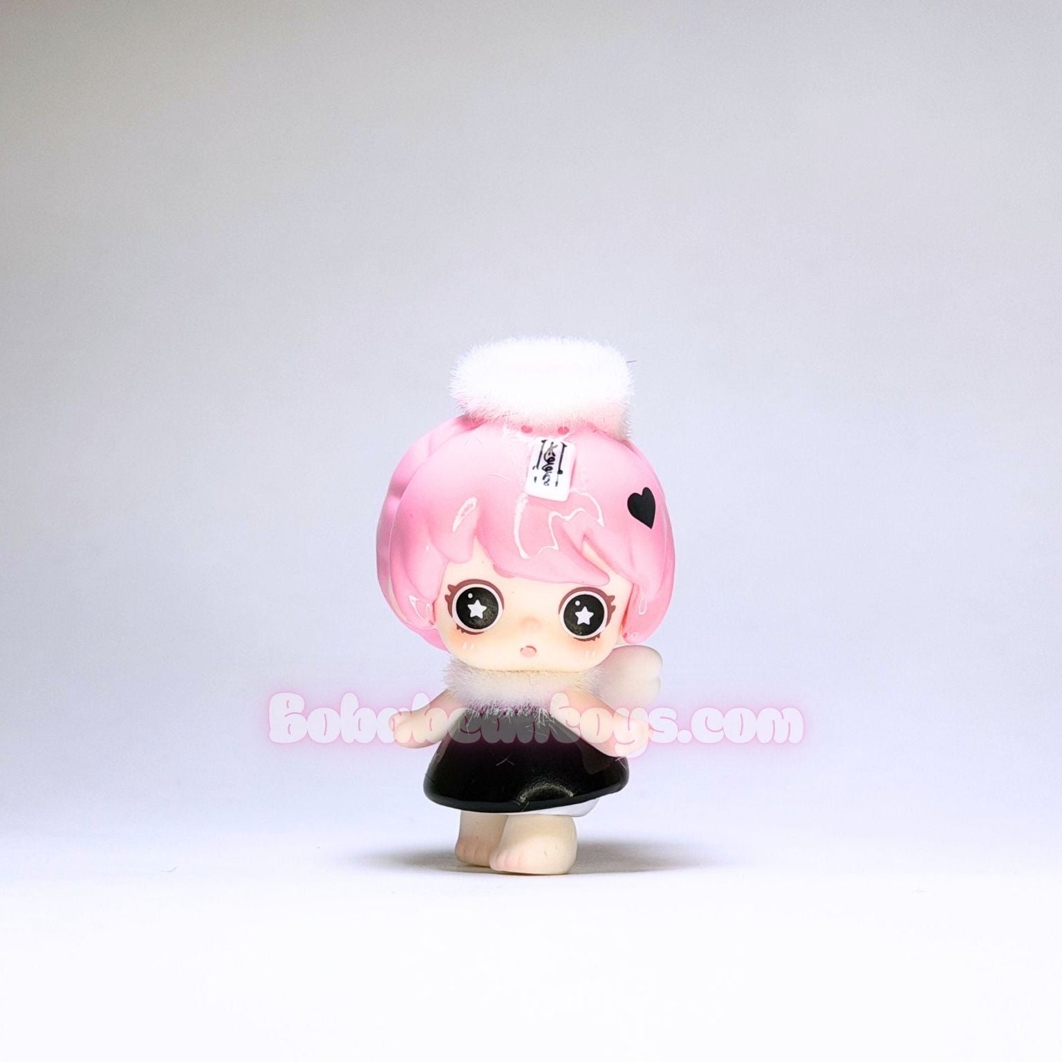 Toy figure with pink hair and black outfit on a white background