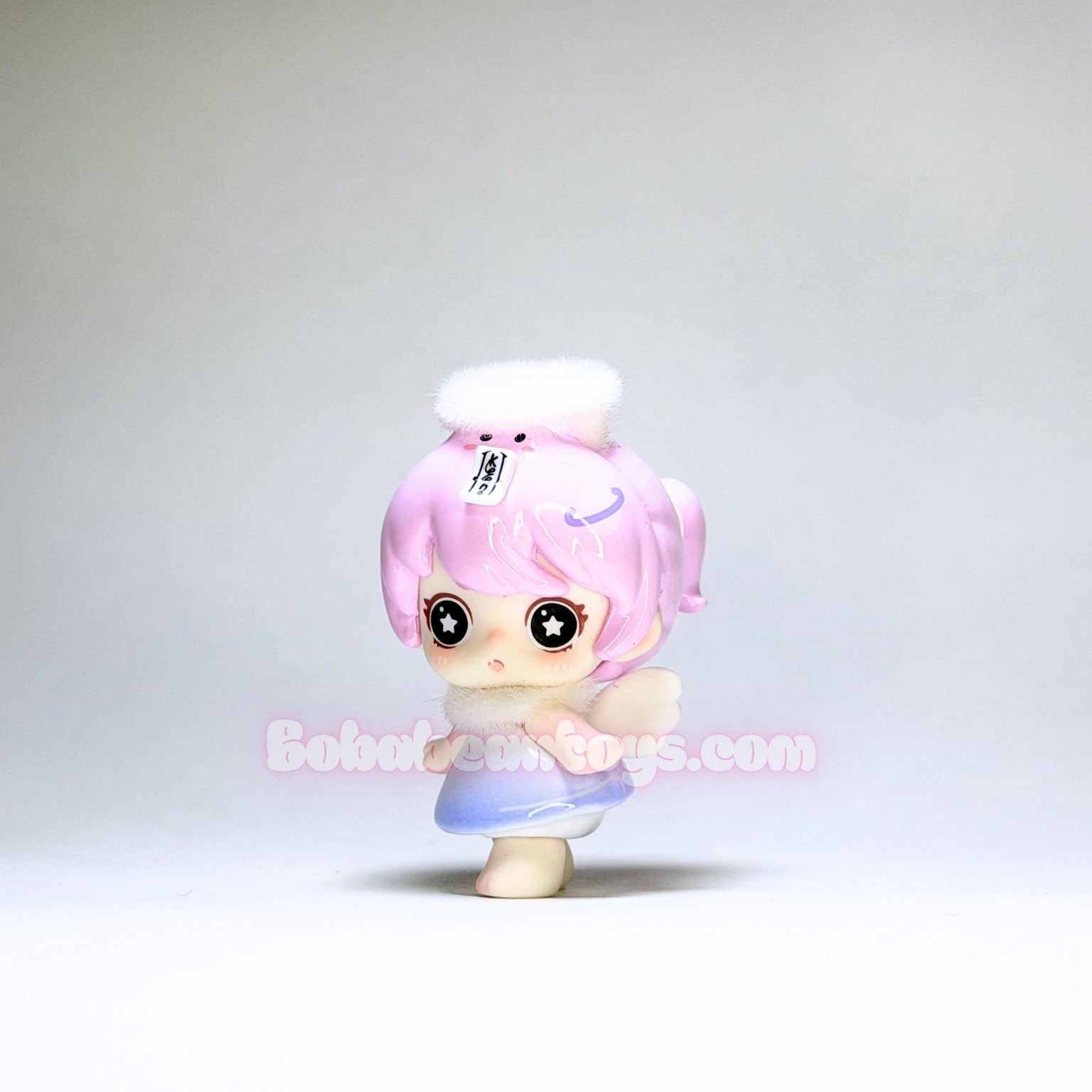 Small figurine with pink hair and a white hat on a plain background