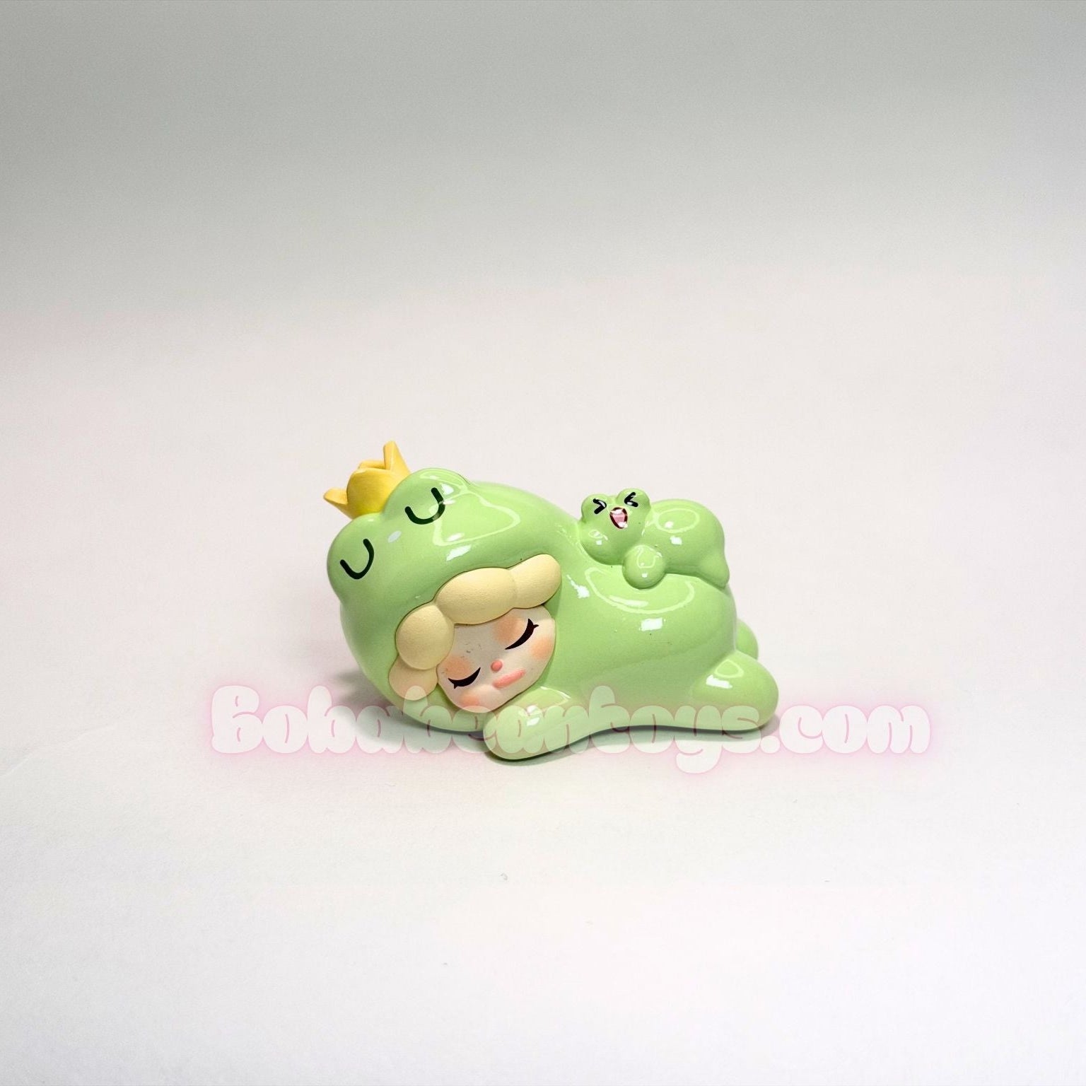 Two green cartoon-like frog characters with closed eyes on a white background