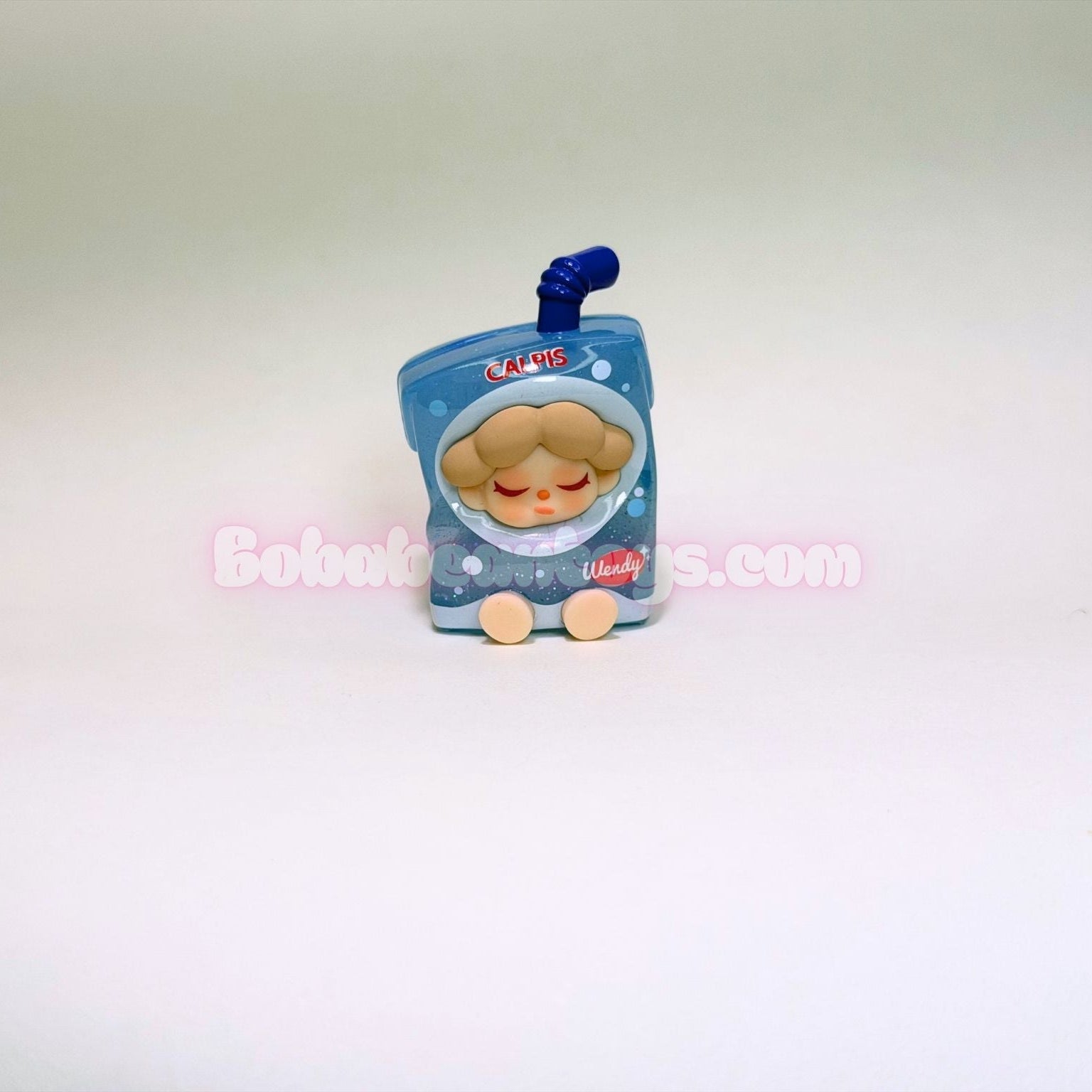 Small toy figure of a character in a blue package  with a blue straw on a white background