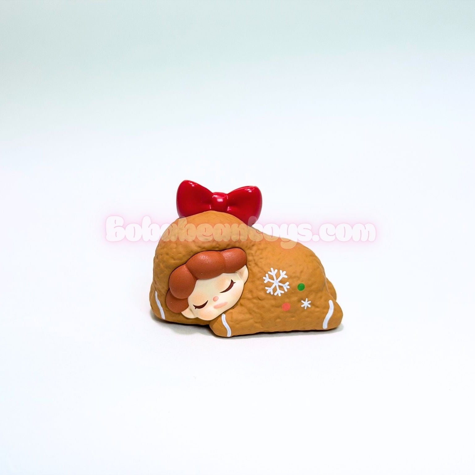 Toy figure of a gingerbread girl with a red bow on a white background
