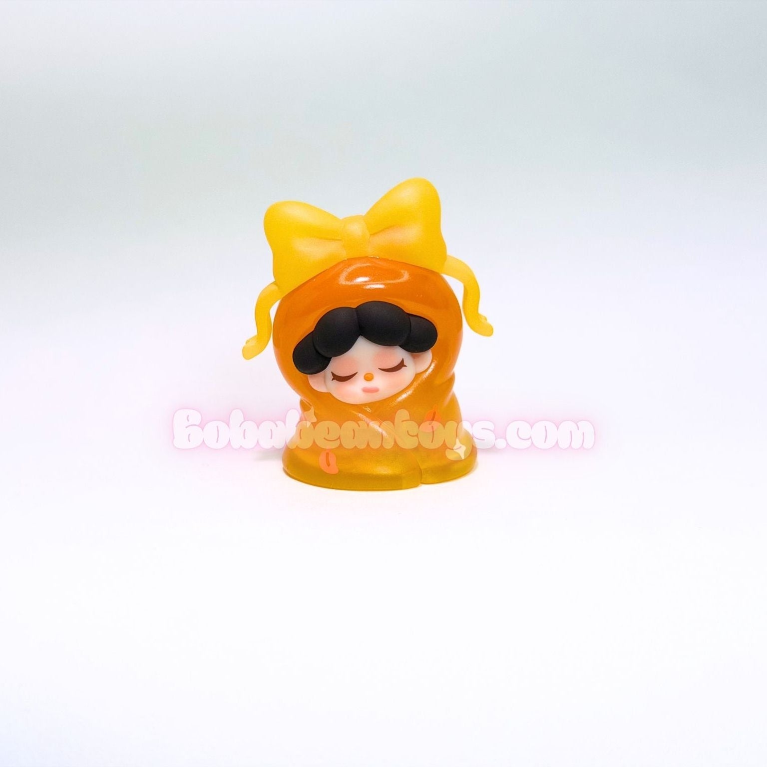Small figurine with a yellow bow on a white background