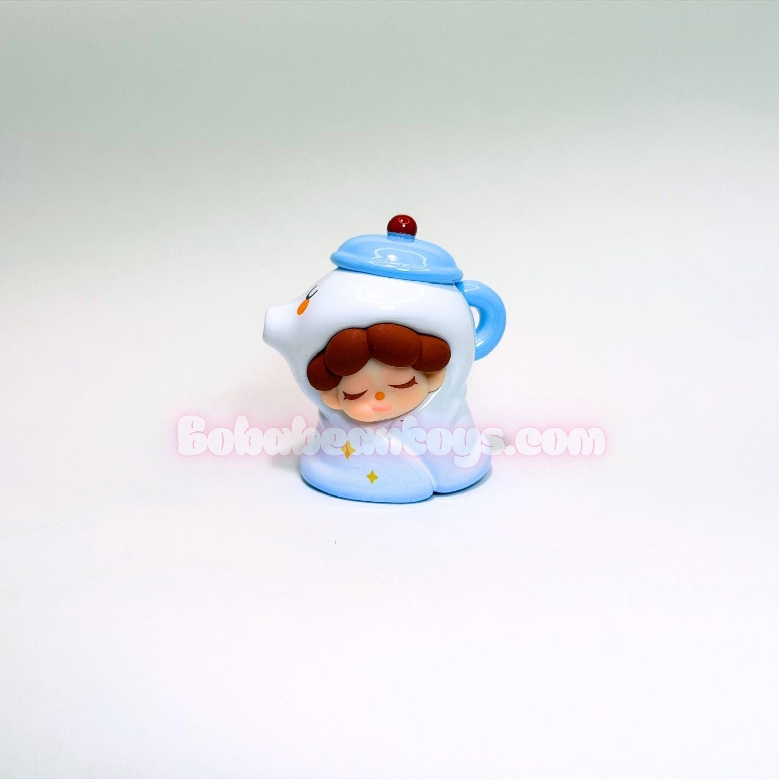 Small figurine of a tea pot on a white background