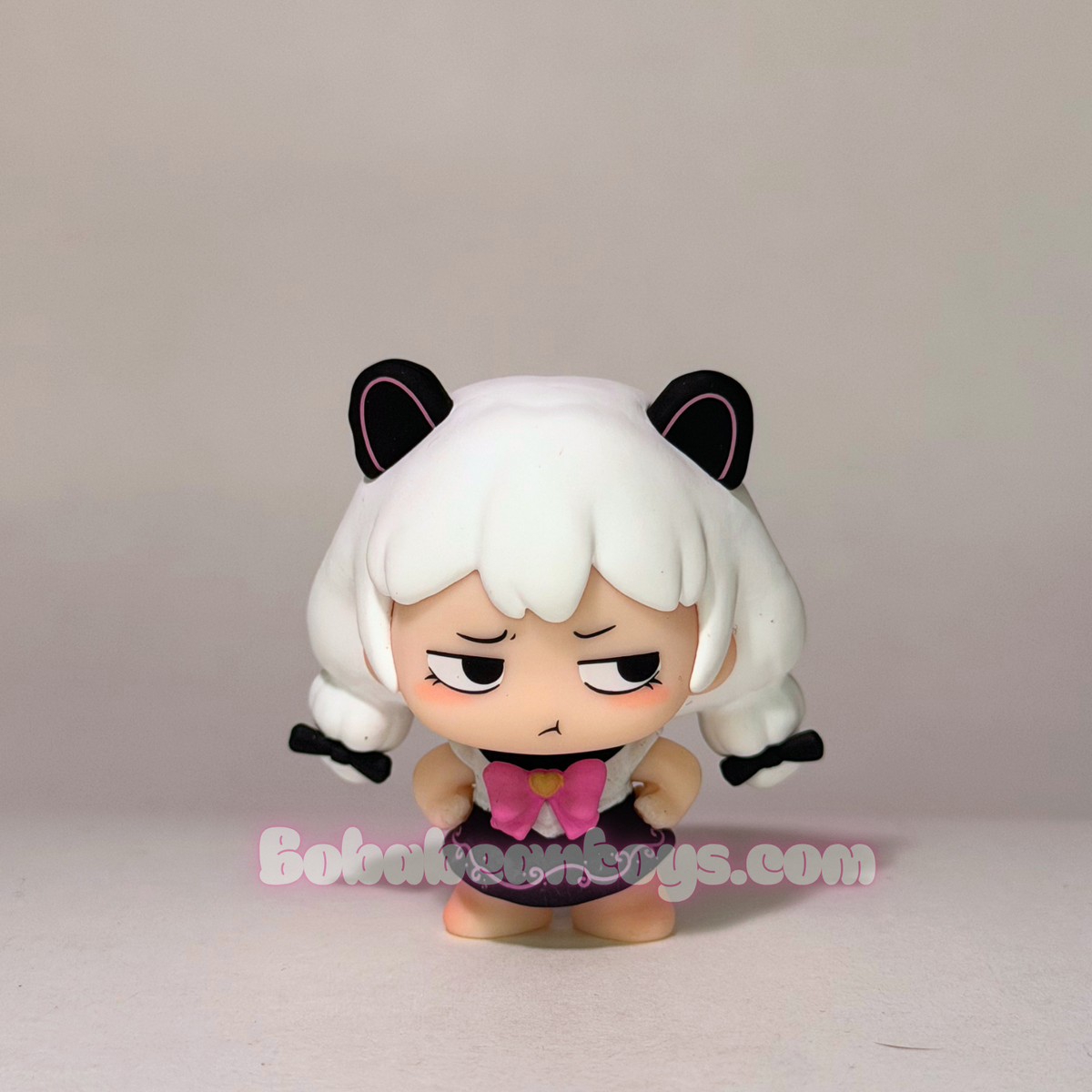 A chibi-style vinyl figure with white hair, black ears, and a pink bow, standing against a plain light gray background. A watermark reading Bobabeantoys.com