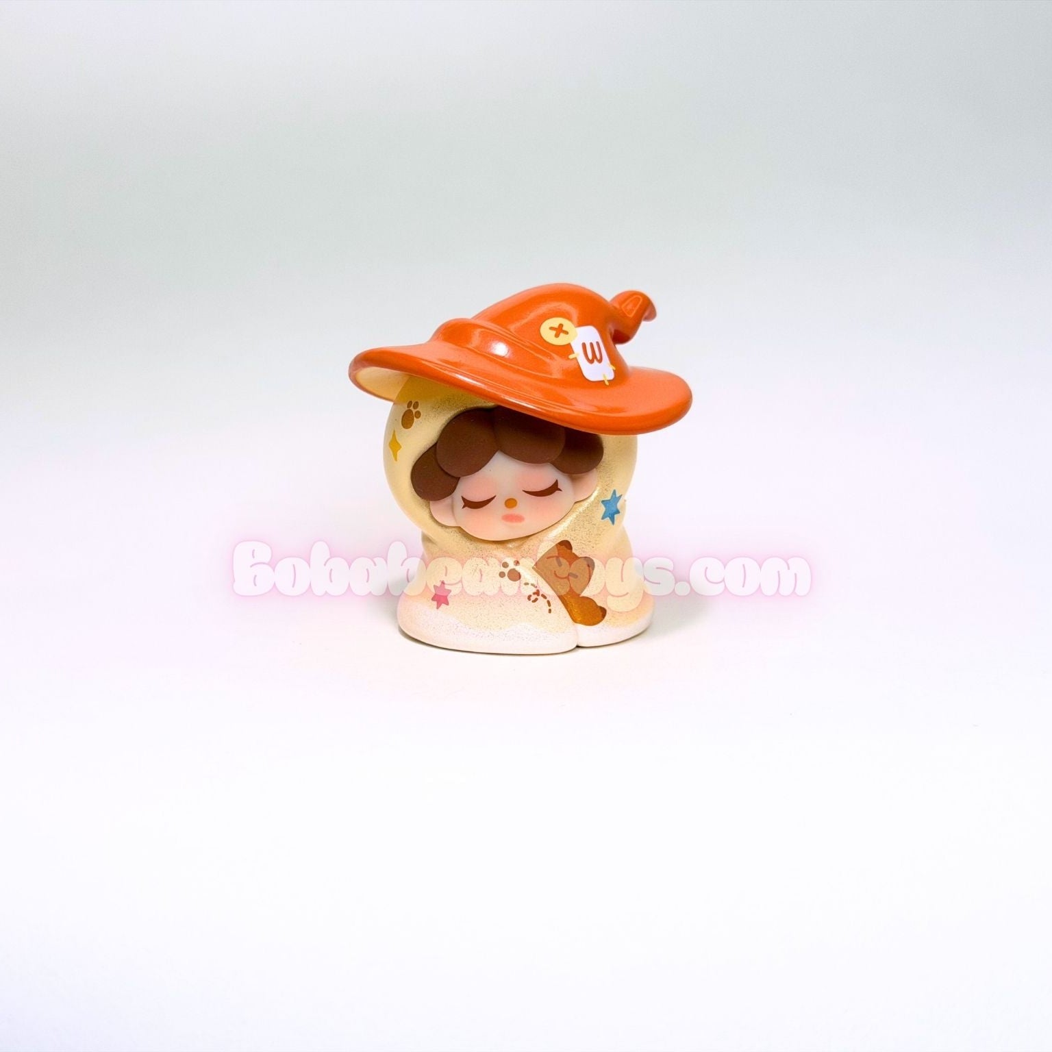 Small figurine of a child wearing a witch's hat on a white background