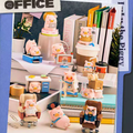 Collection of small office-themed figurines on a desk with books and stationery.