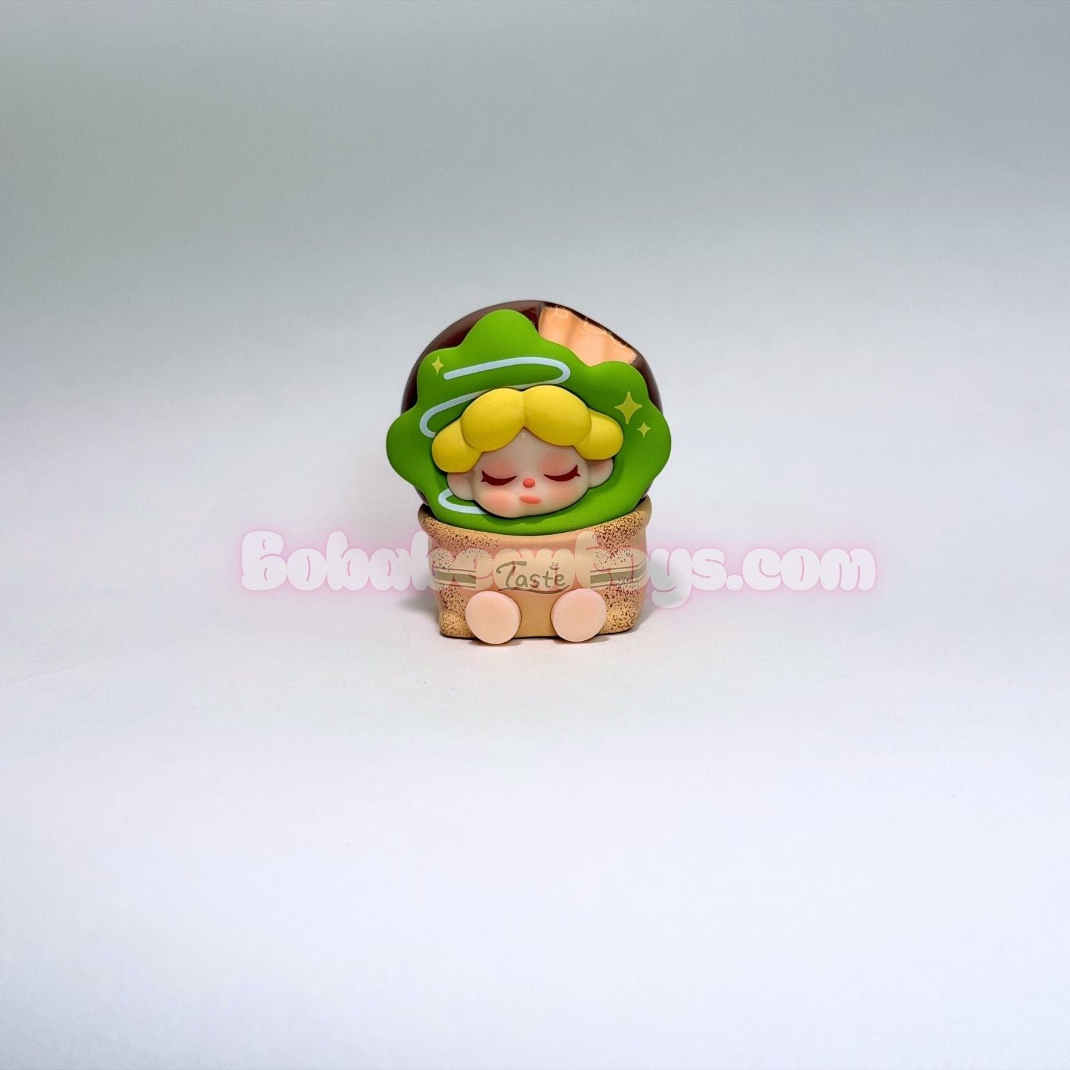 Small figurine of a green donut on a white background