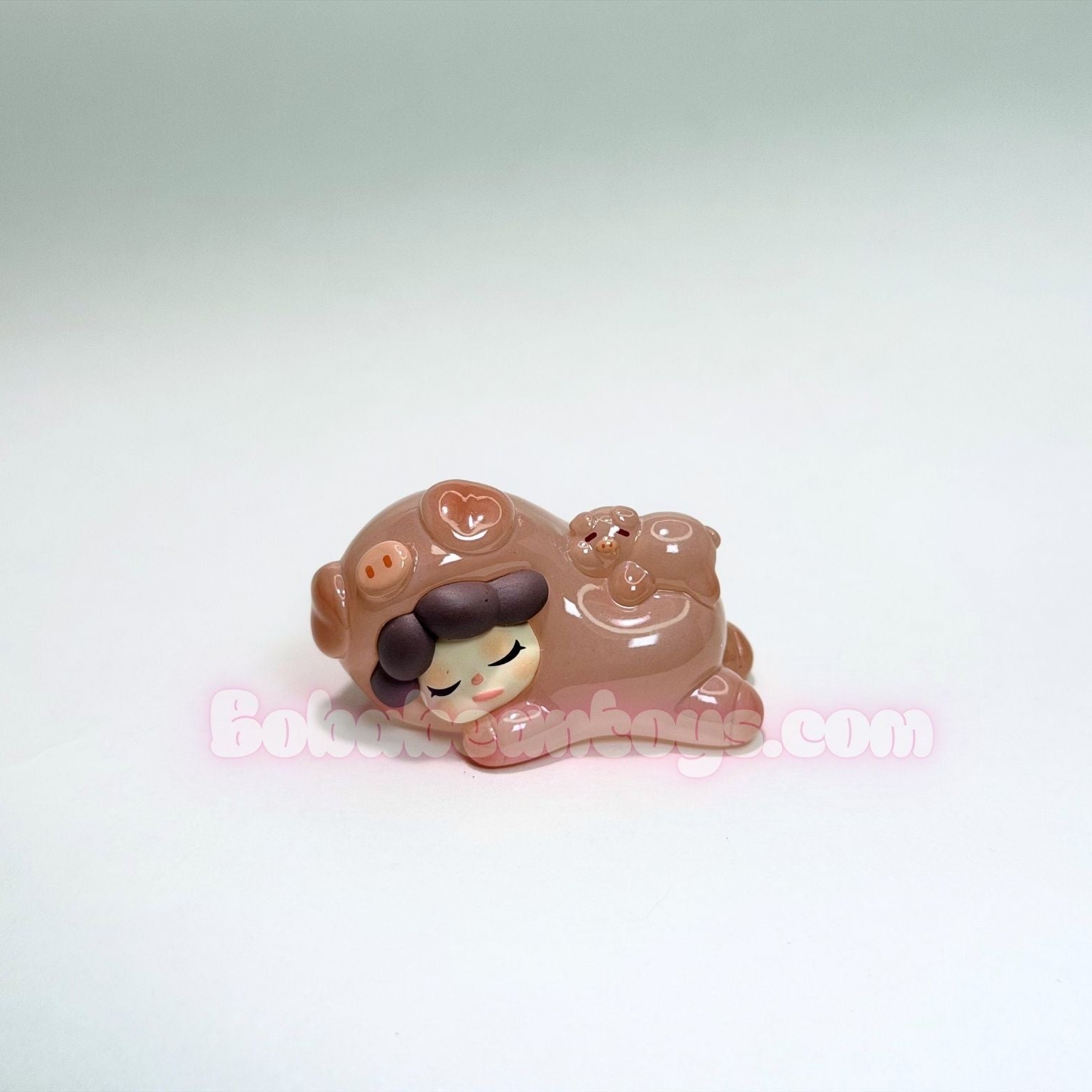 Small toy figure of a pig with a sad expression on a white background