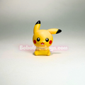 A small yellow Pikachu figurine standing upright on a light gray studio background, with black-tipped ears and cheeks, red circular cheeks, and a translucent Bob's Toys watermark across the center.