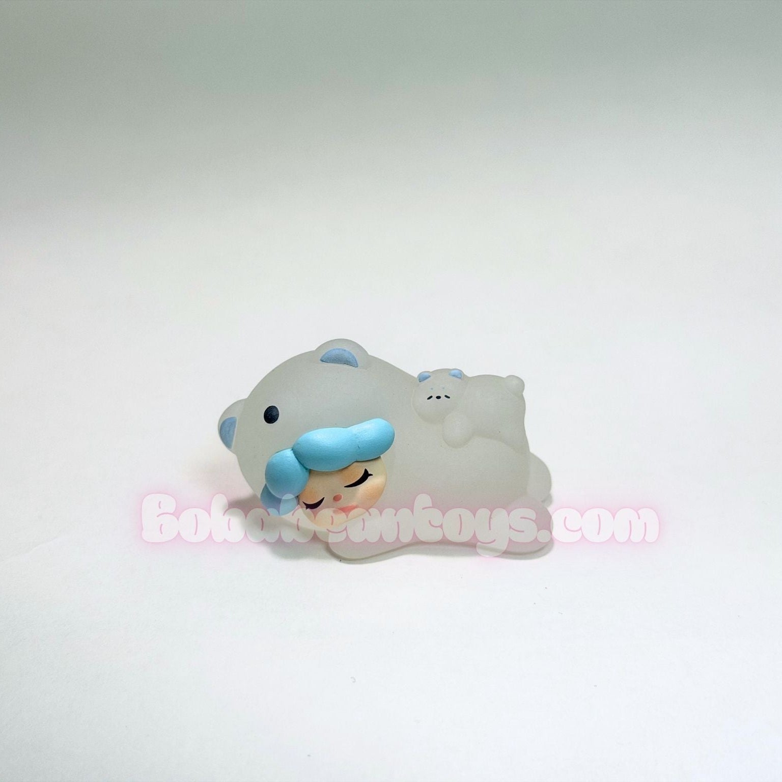 Small figurine of a character with blue hair and a white outfit on a light gray background.