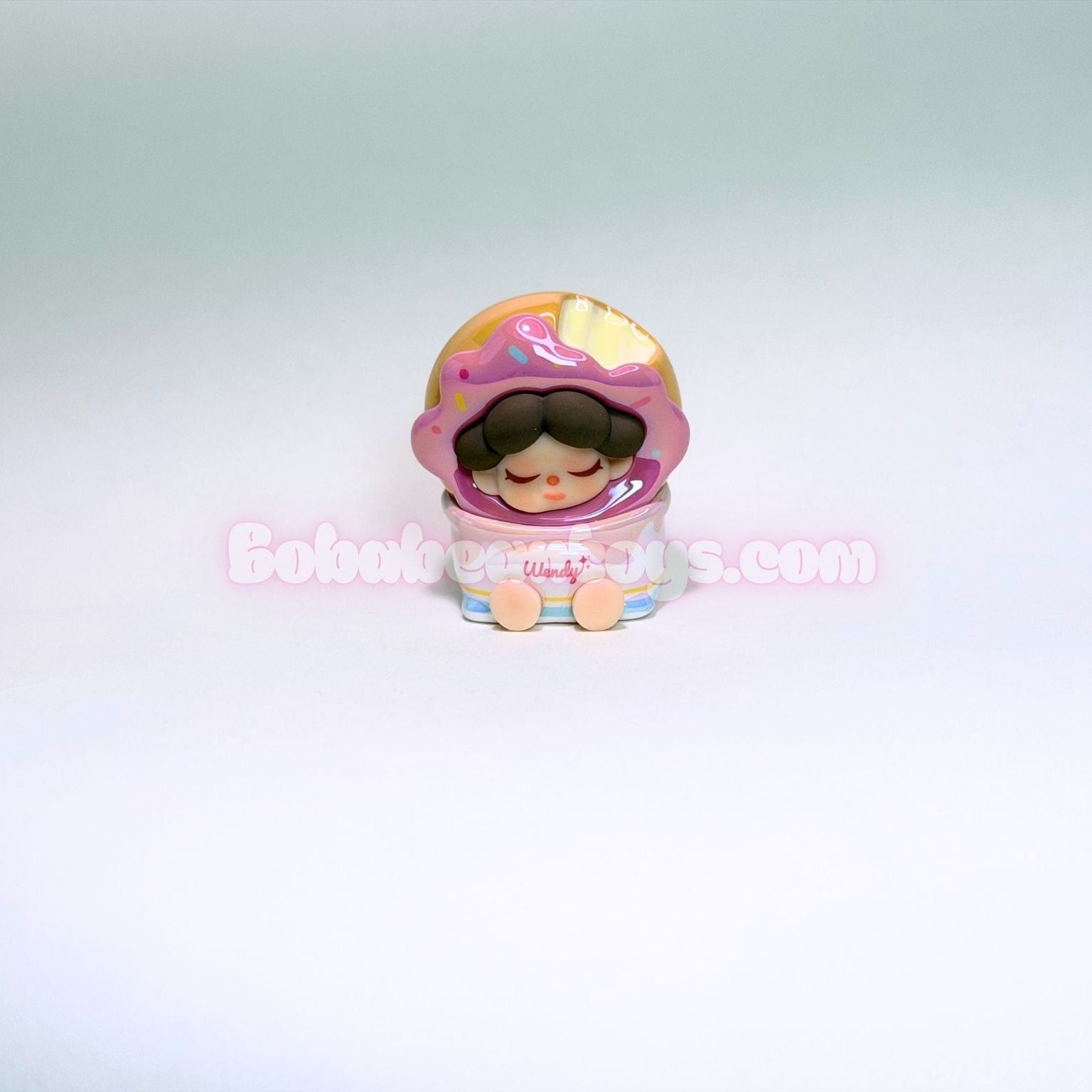 Small figurine of a pink donut on a light gray background