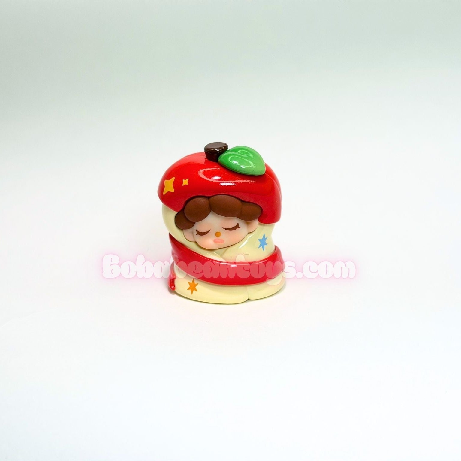 Small figurine dressed as a red apple on a white background