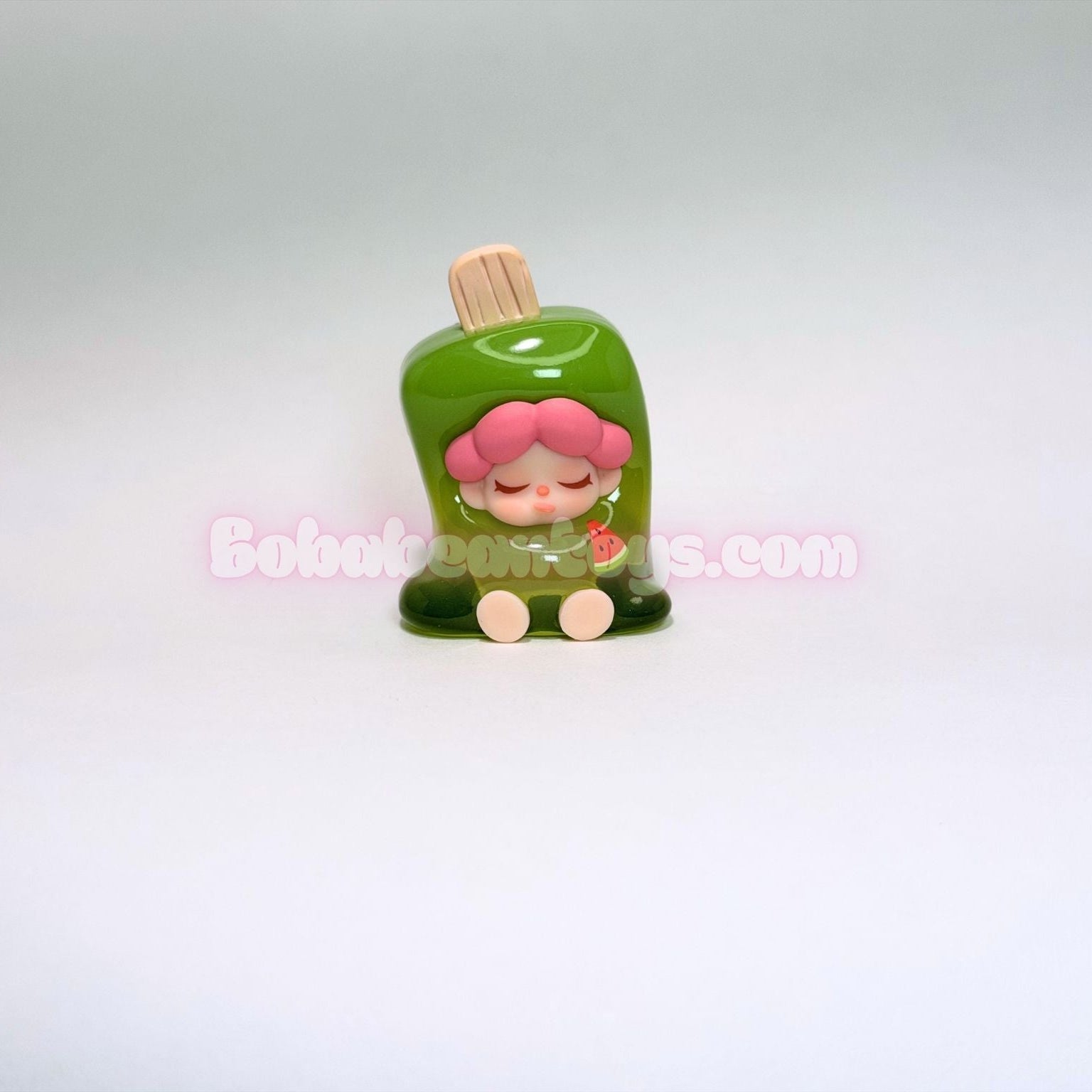 Small figurine of a character with pink hair and a green ice popsicle on a white background