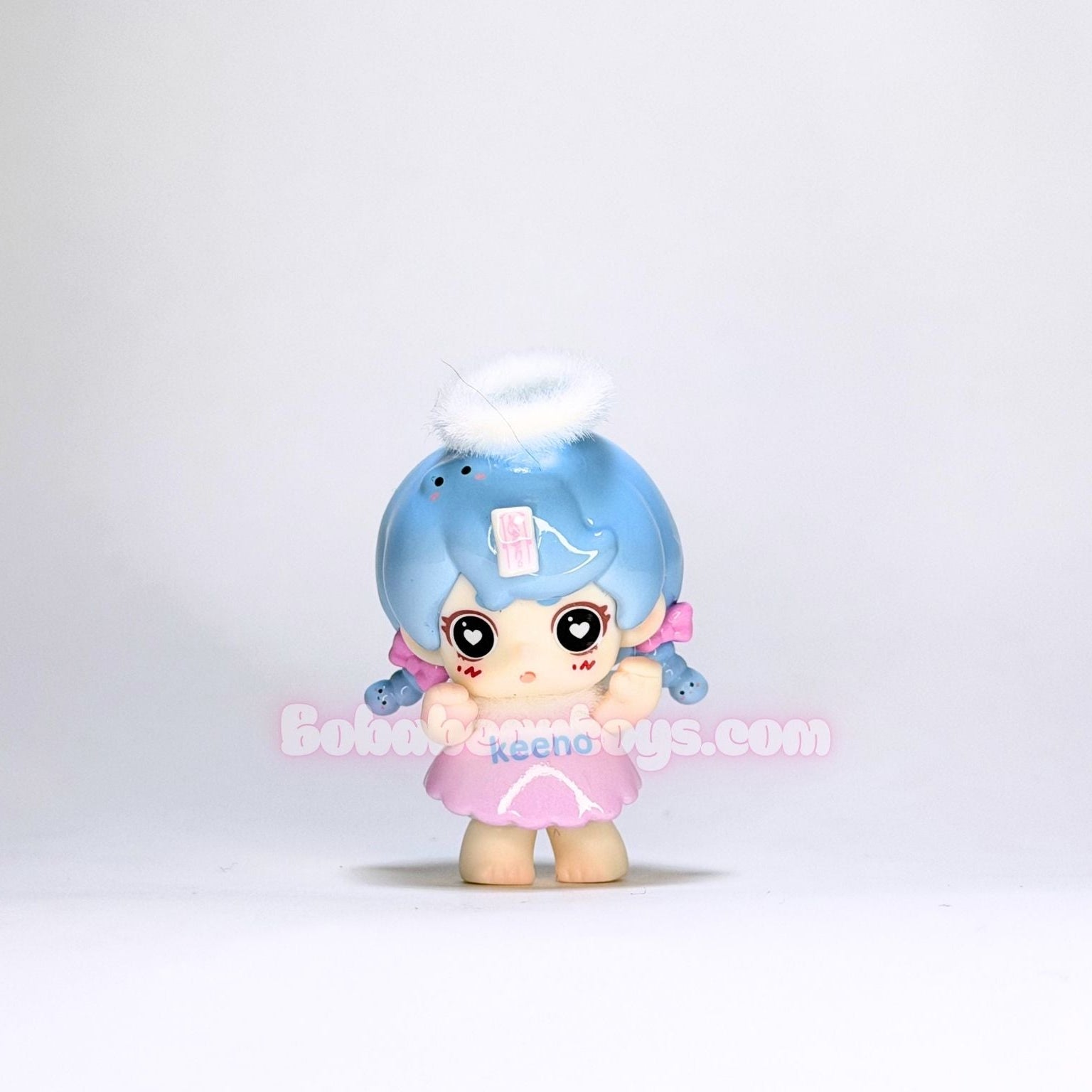 Small figurine with blue hair and a pink outfit on a white background