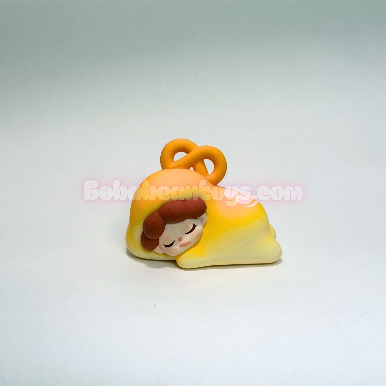 Small figurine of a character with a yellow outfit and orange hair accessory on a light gray background.