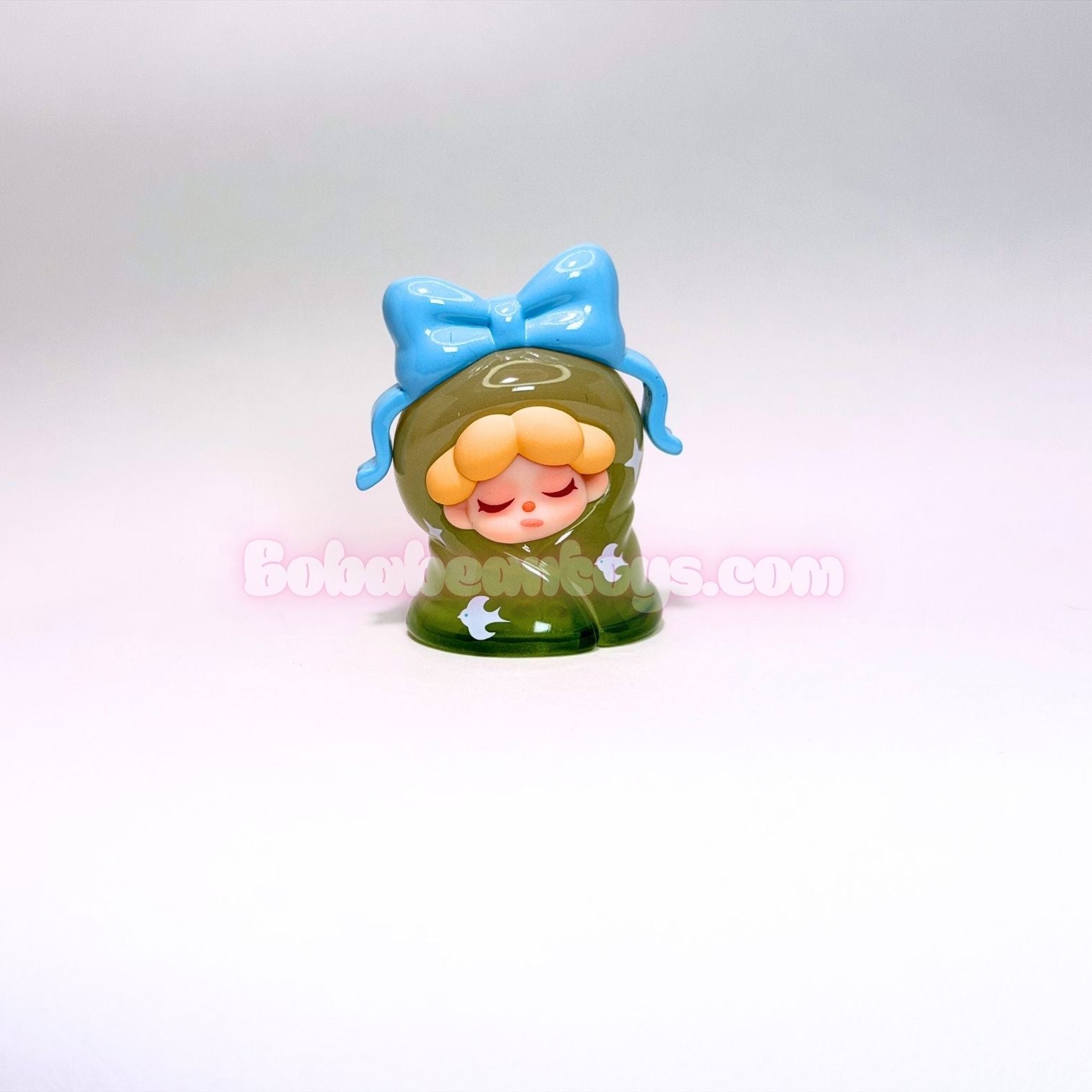 Small figurine with a blue bow on a light gray background