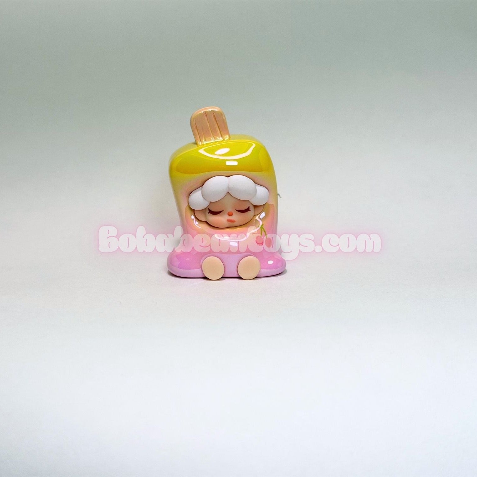 Small figurine with a yellow top and pink base on a white background