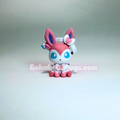 A small pink and white toy figurine with blue eyes and long pointed ears, shown centered on a plain light gray background. A semi-transparent watermark reading Bobitoyos.