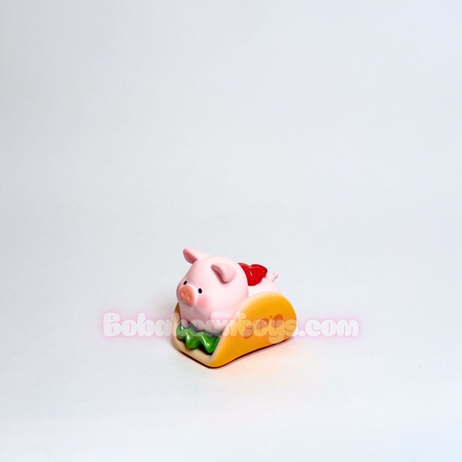 Small pink piggy sitting inside a taco shell on a white background