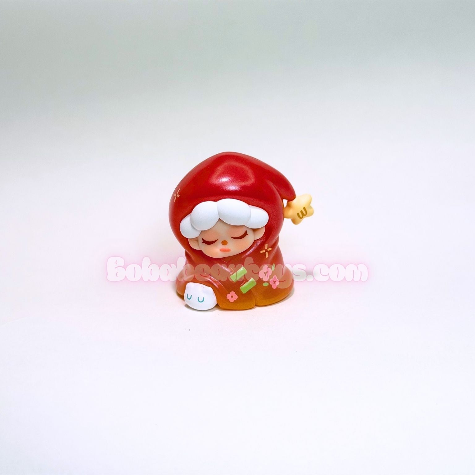 Small figurine with red hair and white face on a light pink background