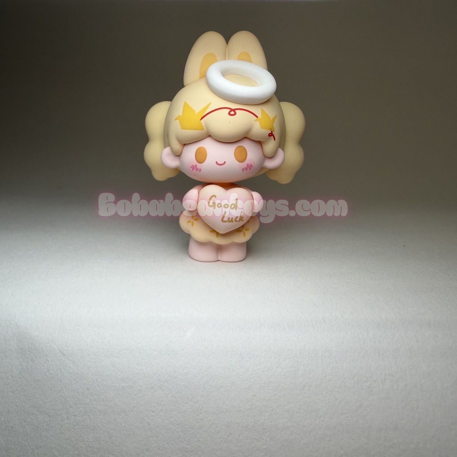 Small angel figurine with a heart and halo on a gray background