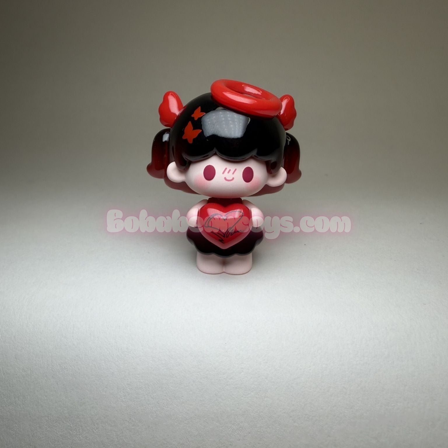 Small figurine with black hair, red hat, and heart-shaped dress on a gray background