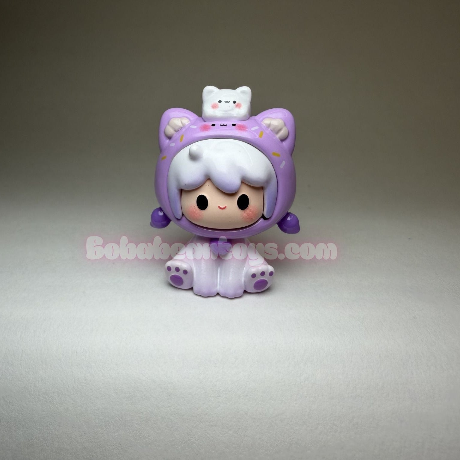 Small purple character figurine with a white hat on a gray background