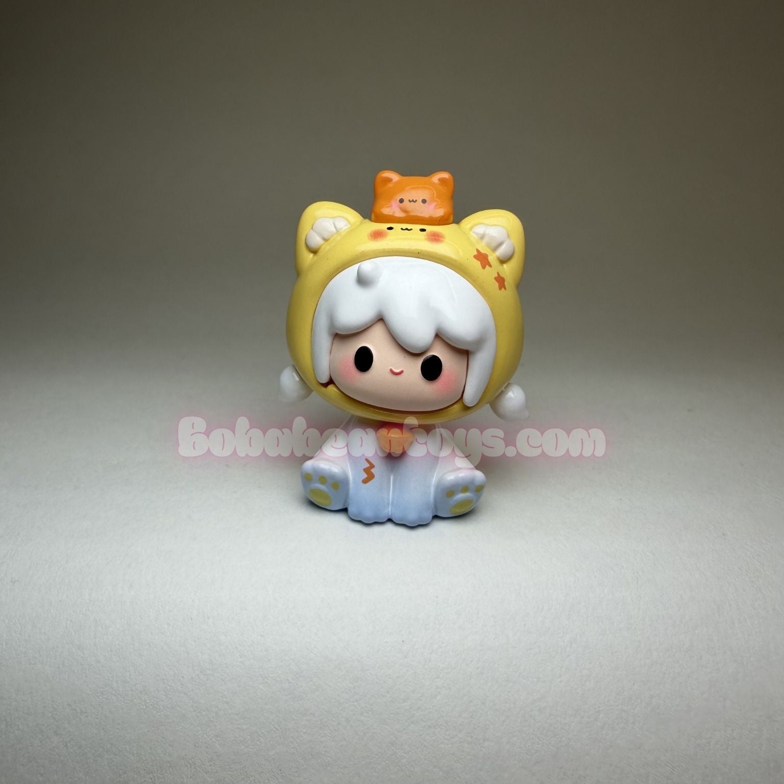 Toy figure with a yellow outfit and white hair on a gray background