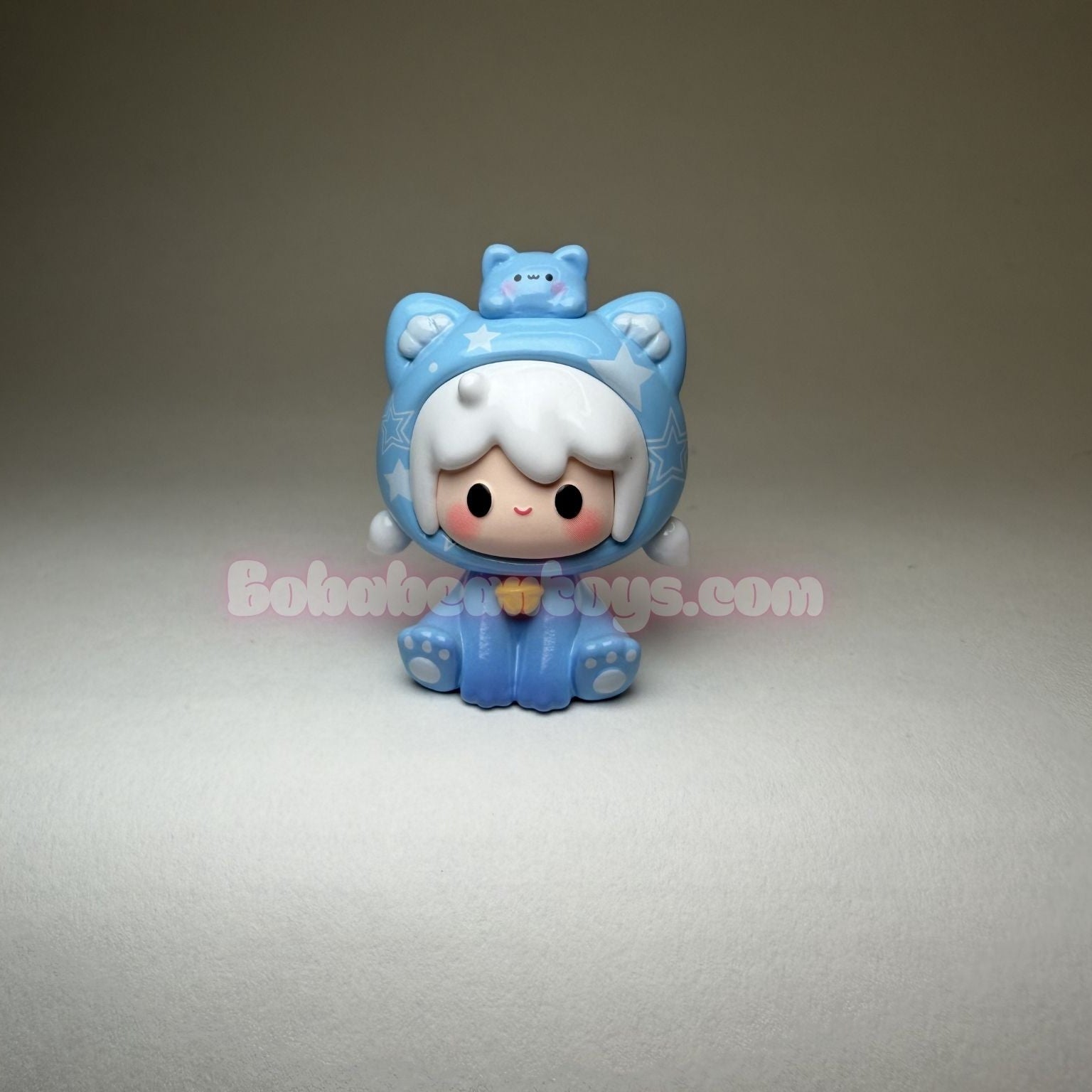 Small blue figurine with cat ears on a gray background