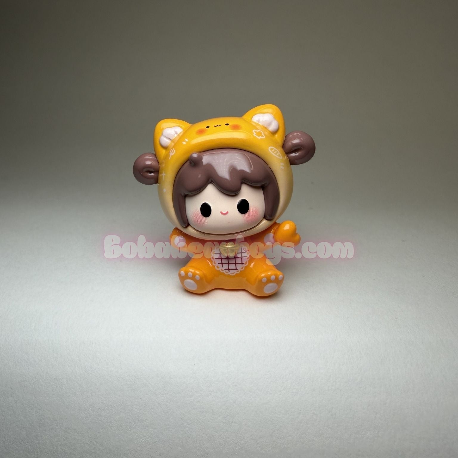 Toy figure of a character wearing an orange hood on a gray background