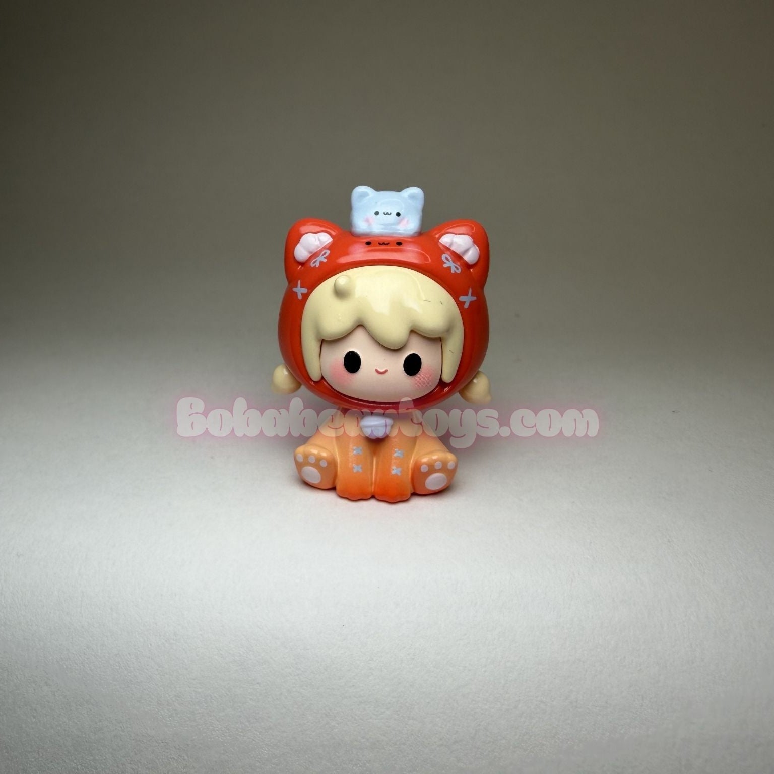 Toy figure with blonde hair and orange and red outfit on a gray background
