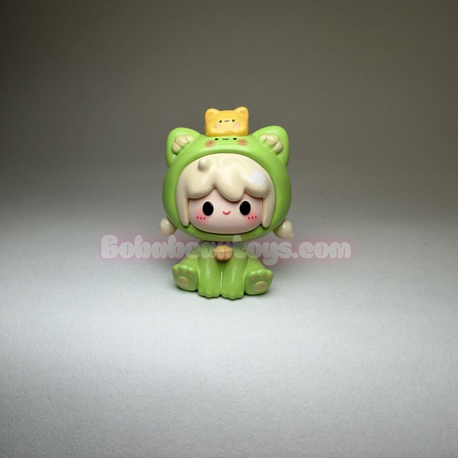 Small green character figurine with a yellow hat on a gray background