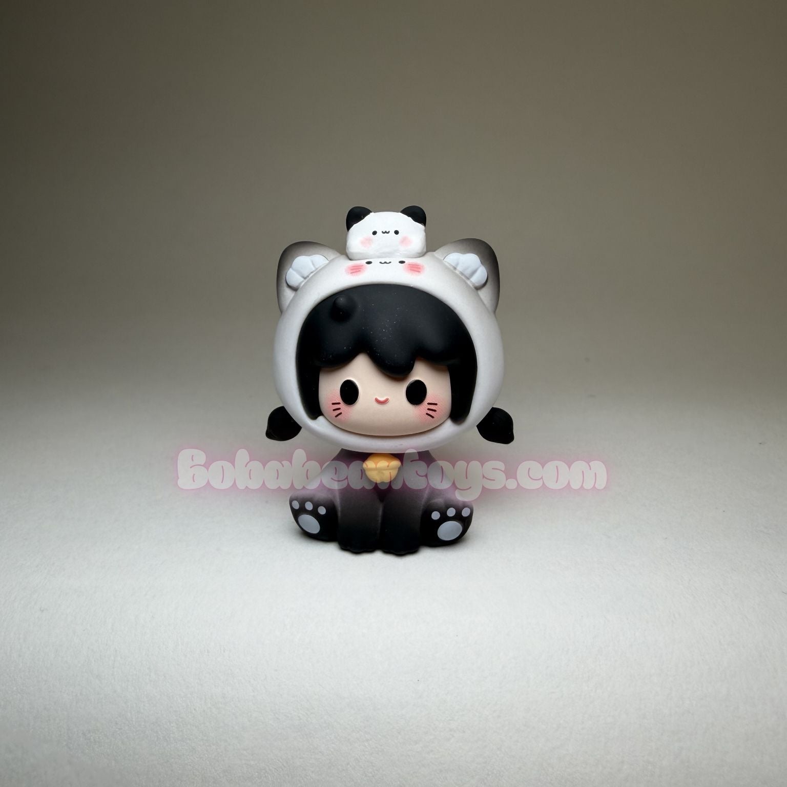 Toy figure with cat ears and black hair on a gray background