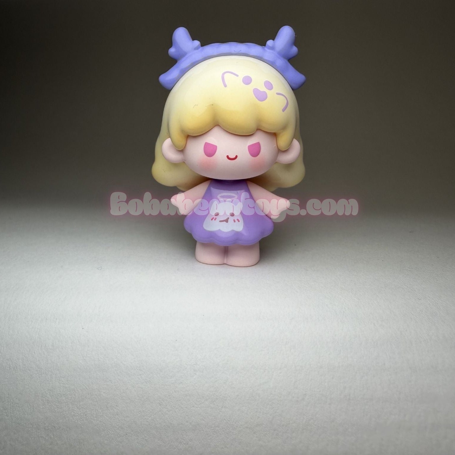 Small figurine with blonde hair and a purple dress on a gray background