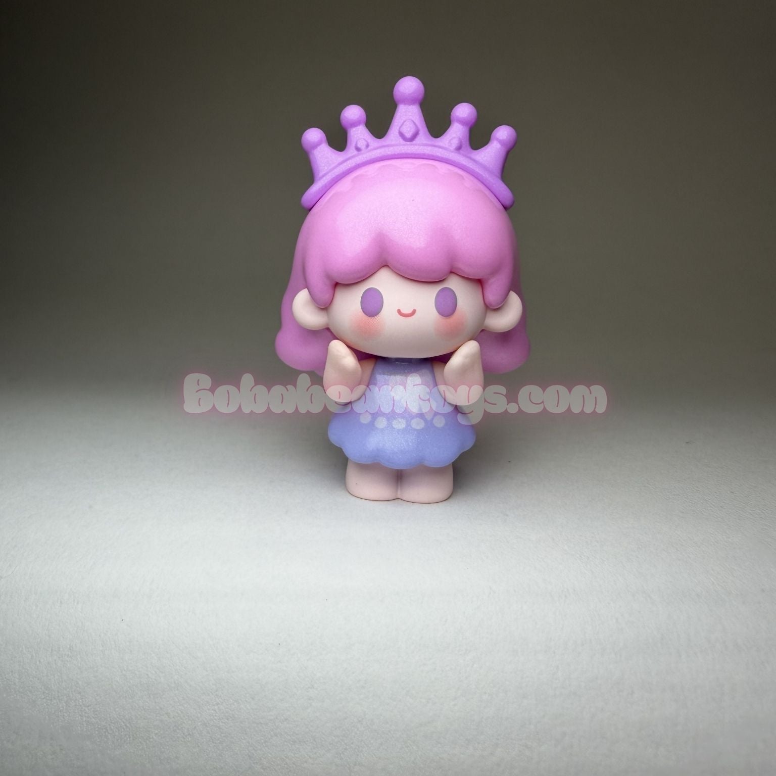 Small figurine with pink hair and a purple crown on a gray background